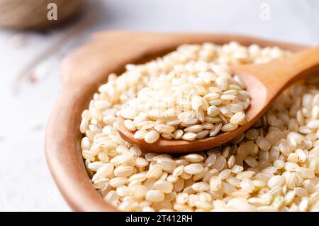 Nahaufnahme von Yamani-Reis in einer Tonschale und einem Holzlöffel. Stockfoto