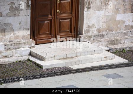 Braune hölzerne Eingangstür eines weißen alten Steingebäudes an einem sonnigen Tag, Nahaufnahme der Architektur der Altstadt, niemand. Stockfoto