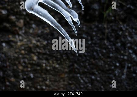 Eisstalaktiten schmelzen, Wassertröpfchen fallen langsam. Eis taut in der Hitze auf. Stockfoto