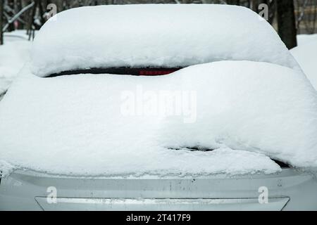 Heckscheibe mit Scheibenwischer, Scheibenwaschanlage und Bremsleuchte, bedeckt mit einer großen Schneeschicht an einem kalten Wintertag. Stockfoto