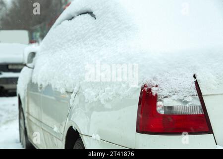 Heckscheinwerfer mit rotem Stopp-Signal, bedeckt mit Schnee bei Winterwetter, Schneeschwankungen auf der Straße und bei anderen Fahrzeugen. Nahaufnahme eines Fahrzeugdepots Stockfoto