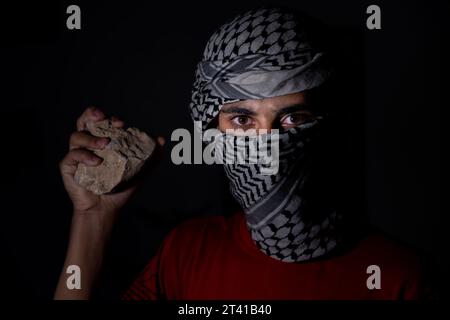 Mann, der Stein hält, um gegen die Besatzung zu kämpfen, bis die Freiheit für sein Land palästina, während er weißen Keffiyeh trägt Stockfoto