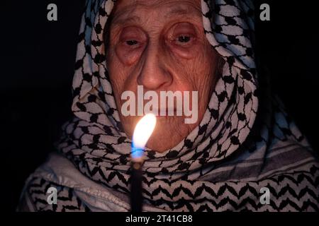 Porträt einer alten Dame, die im Dunkeln weißen palästinensischen Keffiyeh trägt und das Licht gegen die Besatzung hält Stockfoto