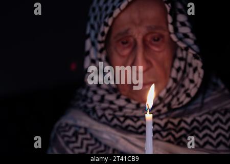 Porträt einer alten Dame, die im Dunkeln weißen palästinensischen Keffiyeh trägt und das Licht gegen die Besatzung hält Stockfoto