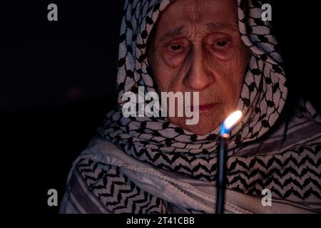 Porträt einer alten Dame, die im Dunkeln weißen palästinensischen Keffiyeh trägt und das Licht gegen die Besatzung hält Stockfoto