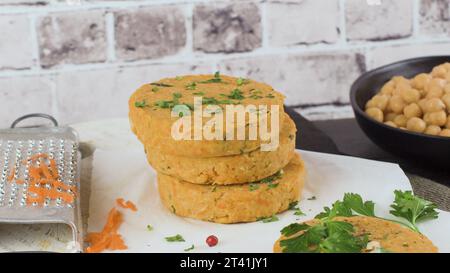 Roher Veggie-Burger mit Kichererbsen, Gemüse und Petersilienblättern auf Küchenarbeitsplättchen. Stockfoto