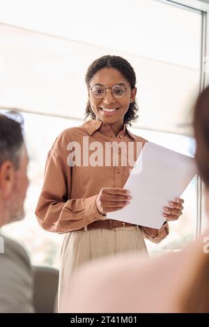 Lächelnde junge afroamerikanische Geschäftsfrau, die bei Gruppentreffen kommuniziert. Stockfoto