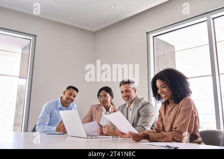 Zufriedene Führungskräfte aus verschiedenen Geschäftsbereichen, die bei Besprechungen im Büro mit Laptop arbeiten. Stockfoto