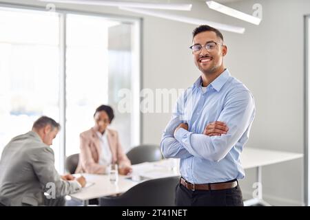 Lächelnder junger lateinamerikanischer Geschäftsmann, der bei einer Bürositzung steht. Hochformat Stockfoto