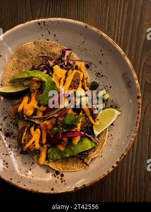 Eine Nahaufnahme von zwei Tacos auf einem Teller, garniert mit einer köstlichen Sauce und garniert Stockfoto