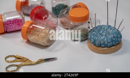 Perlen und Nadel auf Nadelkissen zum Nähen auf weißem Hintergrund Nahaufnahme. Stockfoto
