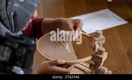 Nähen Tutorial Delight: Nähte für Damenhände auf dunklem Stoff Stockfoto