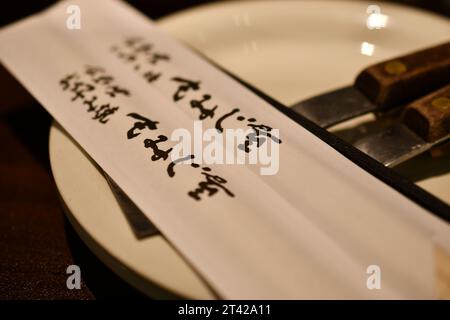 Eine Nahaufnahme chinesischer Essstäbchen mit hieroglyphen Schriften auf einem Teller Stockfoto