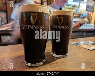 Ein Holztisch mit zwei Gläsern dunklem, schaumigem Guinness-Bier, das nebeneinander in Dublin, Irland, serviert wird Stockfoto