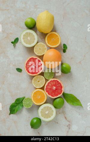 Eine lebhafte Auswahl an Zitrusfrüchten, einschließlich Orangen, Zitronen und Limetten, in einer hellgelben Schüssel auf einer Ebenen Oberfläche angeordnet Stockfoto