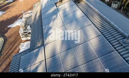 Blick aus der Vogelperspektive mit Blick auf frostige Solarpaneele auf einem privaten Hausdach, sonniger Morgen Stockfoto