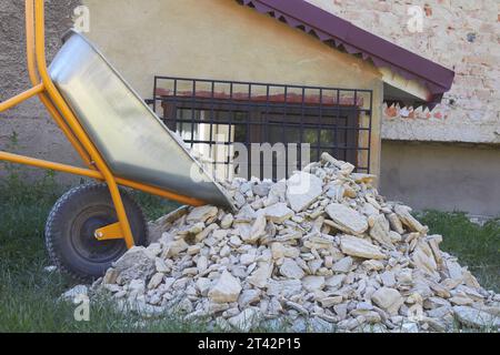 Alter Putzhaufen mit Schubkarre vor dem Haus Stockfoto