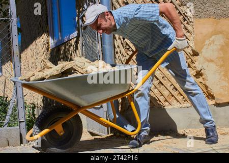 Der Mann schiebt eine Schubkarre voller Bauschutt Stockfoto