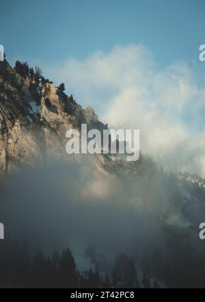 Ein Landschaftsbild mit einer in Nebel gehüllten Bergkette, bei der der Nebel tief über der Bergkette hängt Stockfoto