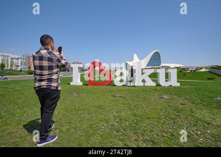 Touristen machen Fotos am ikonischen I Love Baku Schild, das auf dem Rasen vor dem Wahrzeichen des Gebäudes steht. Im Heydar Aliyev Centre Arts pe Stockfoto