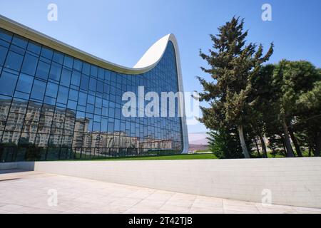 Rückansicht der Glasfassade mit hohen Bäumen. Im Heydar Aliyev Centre Arts Performance Hall in Baku, Aserbaidschan. Stockfoto