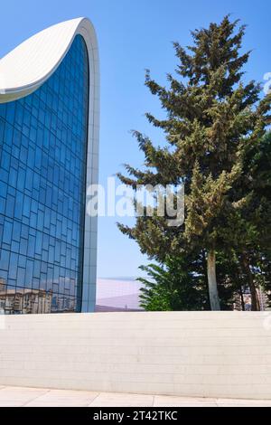 Rückansicht der Glasfassade mit hohen Bäumen. Im Heydar Aliyev Centre Arts Performance Hall in Baku, Aserbaidschan. Stockfoto