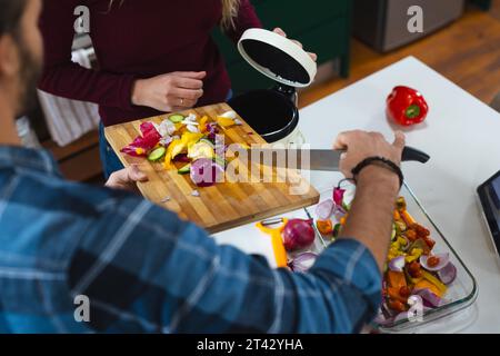 Mittelteil des kaukasischen Paares, das Essen zubereitete, Gemüseabfälle in der Küche kompostierte Stockfoto
