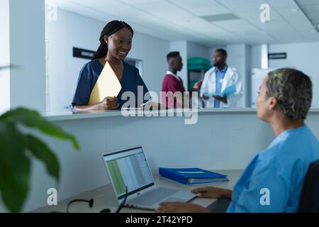 Diverse Ärztinnen diskutieren über die Arbeit an der Rezeption im Krankenhaus Stockfoto