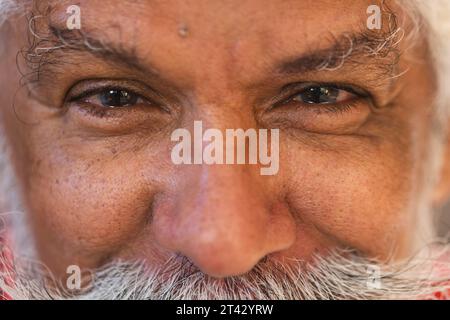 Augen eines glücklichen, birassischen Seniorenmannes mit langem Bart, lächelnd im Töpferstudio Stockfoto