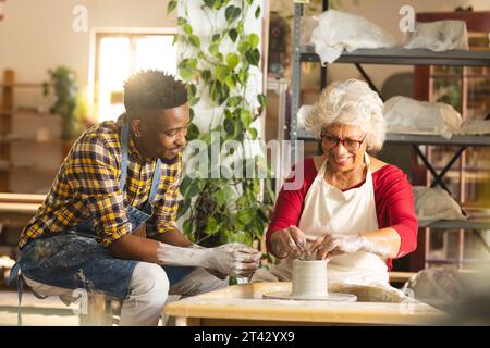Zwei verschiedene männliche und weibliche Töpfer arbeiten mit Töpferrad an Tonvase im Töpferstudio Stockfoto