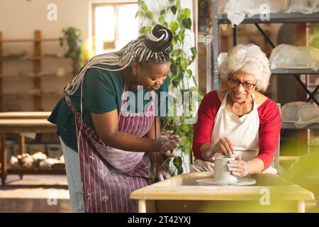 Zwei verschiedene Töpferinnen arbeiten an Tonvasen mit Töpferrad im Töpferstudio Stockfoto