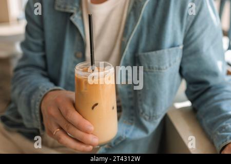 Nahaufnahme eines Mannes, der in einem Café sitzt und ein Glas Eiskaffee hält Stockfoto