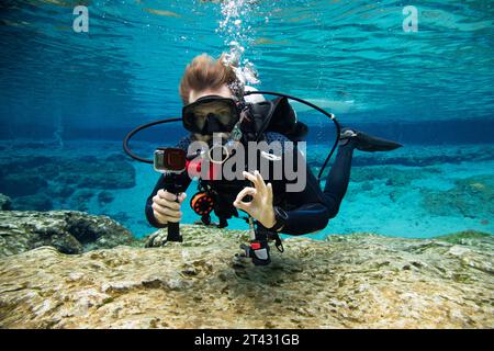 Unterwasserporträt eines Tauchers, der in der Nähe des Meeresbodens schwimmt, macht ein OK-Schild, USA Stockfoto