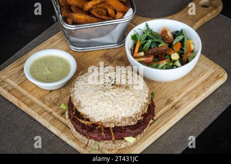 Nahaufnahme eines Rote-Bete-Bohnen-Burgers mit Süßkartoffelfritten, Salat und Dippsoße Stockfoto