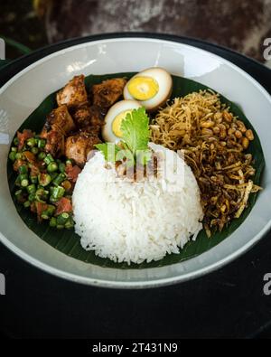 Nahaufnahme eines traditionellen Frühstücks mit Reis, Ei, Pommes Frites und Huhn (Nasi Balap Puyung), Lombok, Indonesien Stockfoto