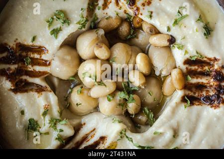 Vollformatansicht einer Schüssel Hummus mit Kichererbsen, Olivenöl und Gewürzen Stockfoto