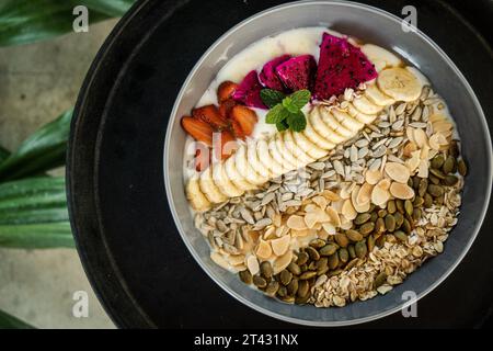 Blick von oben auf eine Schüssel Joghurt mit frischen Erdbeeren, Drachenfrüchten, Bananen, Nüssen und Samen Stockfoto