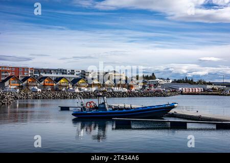 Reykjavik, Island - 25. September 2023: Blaues Schlauchboot im Hafen von Karsnes, Kopavogur. Farbenfrohe Hütten entlang der Küste im Hinterland Stockfoto