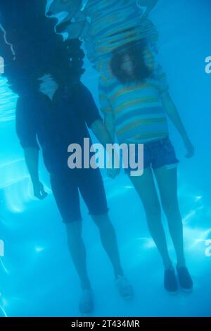 Hände halten, schwimmen und ein Paar unter Wasser aus Liebe, Unterstützung oder Vertrauen in die Beziehung. Körper, Stehen und ein Mann und eine Frau mit Sorgfalt, Zuneigung Stockfoto