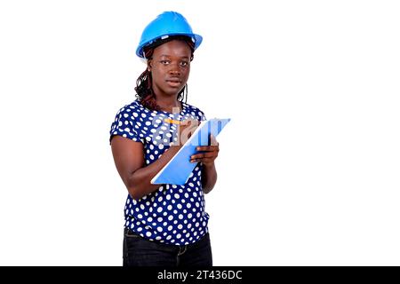Junge Bauingenieurin mit blauem Schutzhelm und Notizen auf Zwischenablage. Stockfoto