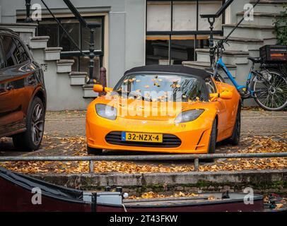 Amsterdam, Niederlande, 26.10.2023, Orange Tesla Roadster von 2011 parkte auf der Straße Stockfoto