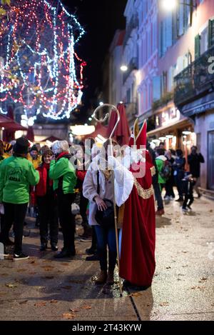 Magische Feiertagsnacht in Carcassonne: Der Weihnachtsmann teilt einen festlichen Moment mit einer Frau im zauberhaften Licht der Weihnachtsbeleuchtung. Stockfoto