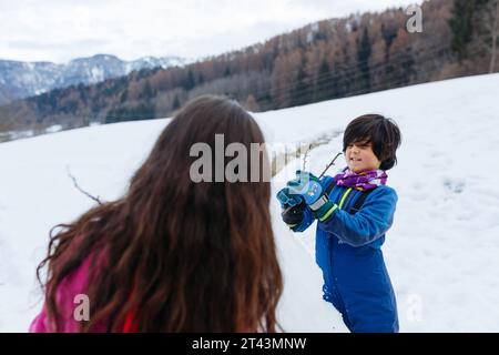 Zwei Mädchen machen Schneemann auf dem schneebedeckten Berg Stockfoto