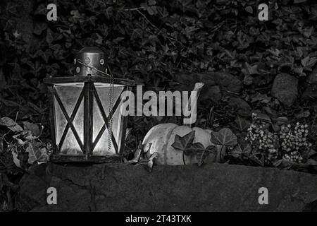 Ein Herbststillleben einer glühenden Kerzenlampe mit einem weißen Kürbis in Schwarz-weiß. Ein guter Look für Halloween. Stockfoto