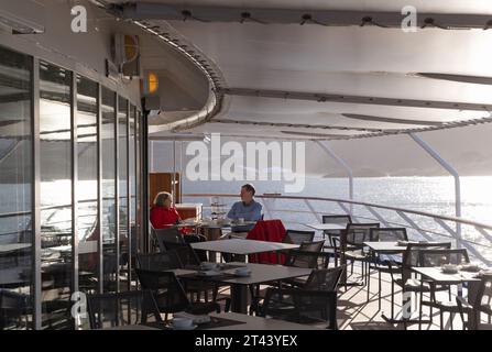 Ein Paar an Bord einer Arktis-Kreuzfahrt, die auf dem Panoramaterdeck spricht, Silversea Cruise Line, Silver Cloud Schiff, Grönland. Arktische Kreuzfahrt. Stockfoto