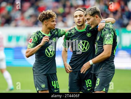 28. Oktober 2023, Bayern, Augsburg: Fußball, Bundesliga, FC Augsburg - VfL Wolfsburg, Spieltag 9, WWK Arena. Kevin Alexander Paredes (l-r), Torschütze Lovro Majer und Jonas Other Wind vom VfL Wolfsburg bejubeln Majers Ziel mit 1:2 an. Foto: Daniel Löb/dpa - WICHTIGER HINWEIS: Gemäß den Vorgaben der DFL Deutsche Fußball Liga und des DFB Deutscher Fußball-Bund ist es verboten, im Stadion und/oder des Spiels aufgenommene Fotografien in Form von Sequenzbildern und/oder videoähnlichen Fotoserien zu verwenden oder verwenden zu lassen. Stockfoto