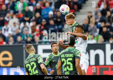 28. Oktober 2023, Bayern, Augsburg: Fußball: Bundesliga, FC Augsburg - VfL Wolfsburg, Spieltag 9, WWK Arena. Der VfL Wolfsburg Nicolas Cozza (TOP) räumt den Ball von Felix Uduokhai des FC Augsburg ab. Foto: Daniel Löb/dpa - WICHTIGER HINWEIS: Gemäß den Vorgaben der DFL Deutsche Fußball Liga und des DFB Deutscher Fußball-Bund ist es verboten, im Stadion und/oder des Spiels aufgenommene Fotografien in Form von Sequenzbildern und/oder videoähnlichen Fotoserien zu verwenden oder verwenden zu lassen. Stockfoto