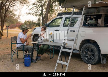 Ein Paar sitzt in tragbaren Stühlen und trinkt Tee. Camping Sommeraktivitäten Stockfoto