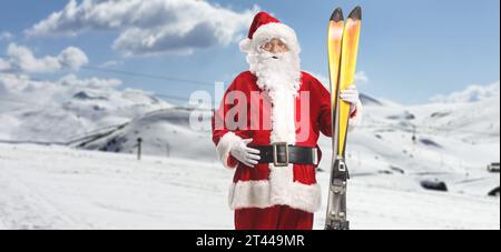 Der Weihnachtsmann hält ein Paar Ski auf einem Berg Stockfoto