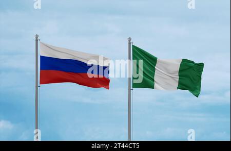 Nigerianische und russische Flaggen schwenken zusammen auf blauem bewölktem Himmel, zwei Länder-Beziehungskonzept Stockfoto